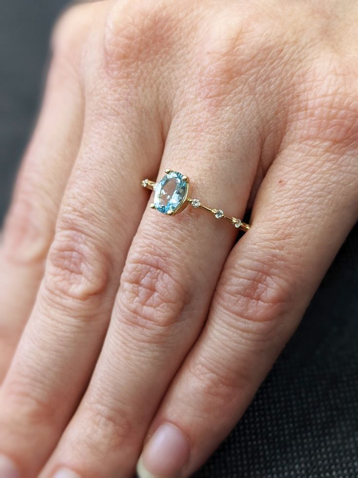 a woman's hand with a ring on it and a blue stone in the middle