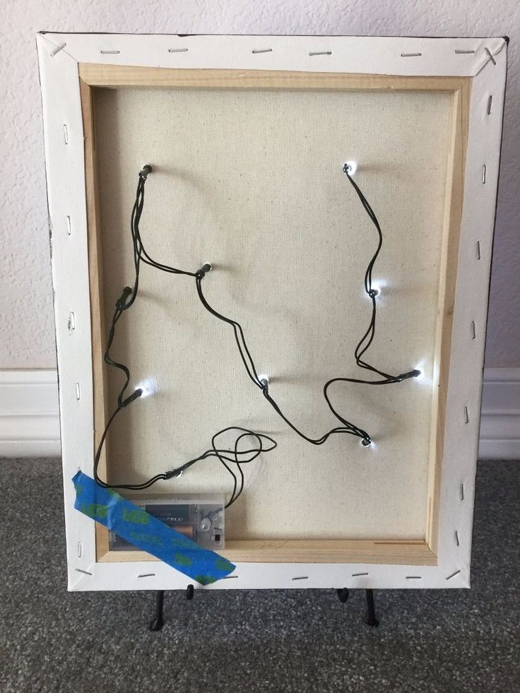 a white frame with string lights in it and a blue ribbon hanging from the side