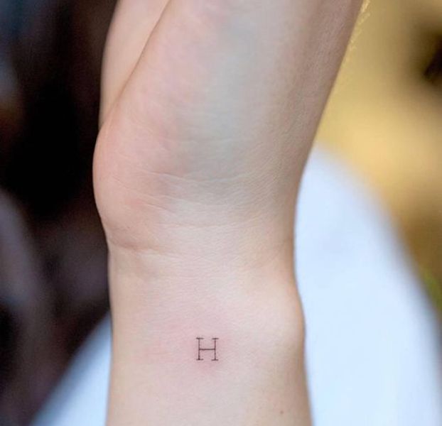 a woman's wrist tattoo with the letter h on it