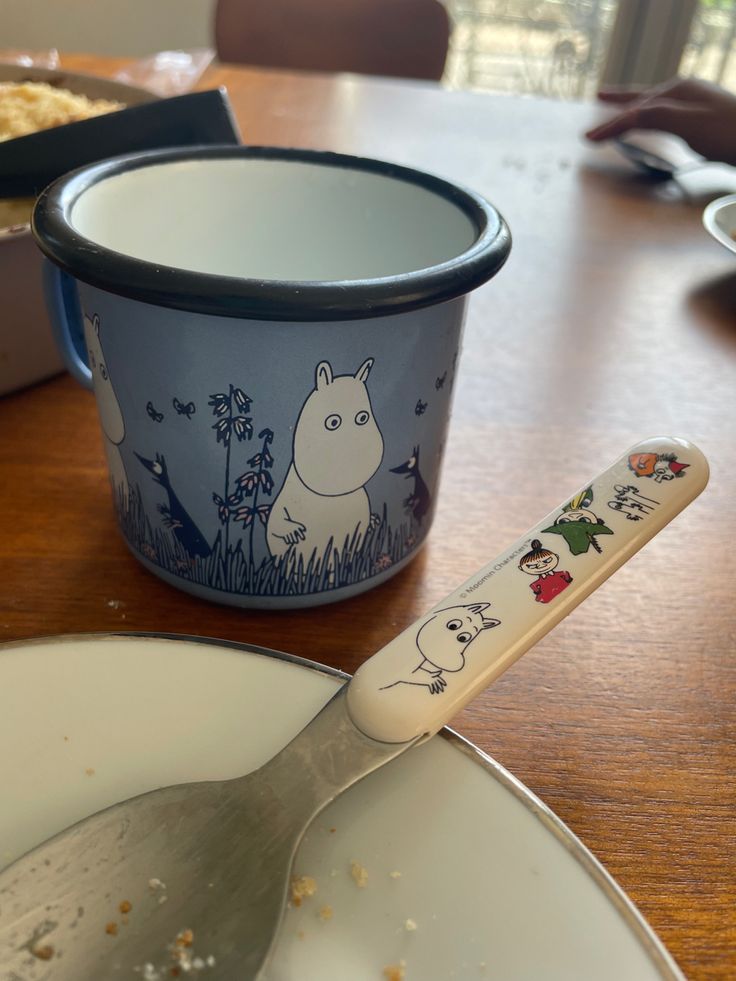 a spoon sitting on top of a white plate next to a bowl with food in it