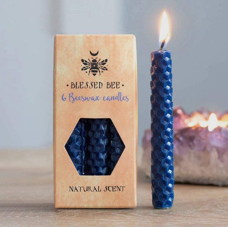 a blue candle sitting next to a box with beeseed bee candles on top of it