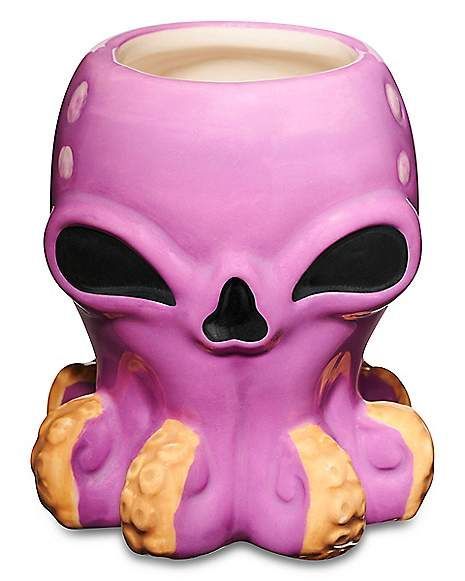 a purple alien mug sitting on top of a table