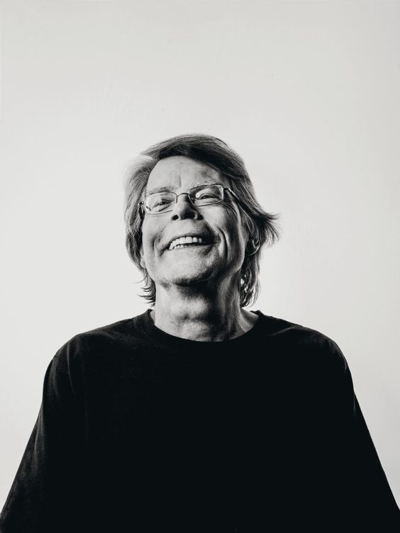 black and white photograph of an older woman with glasses looking up at the sky, smiling