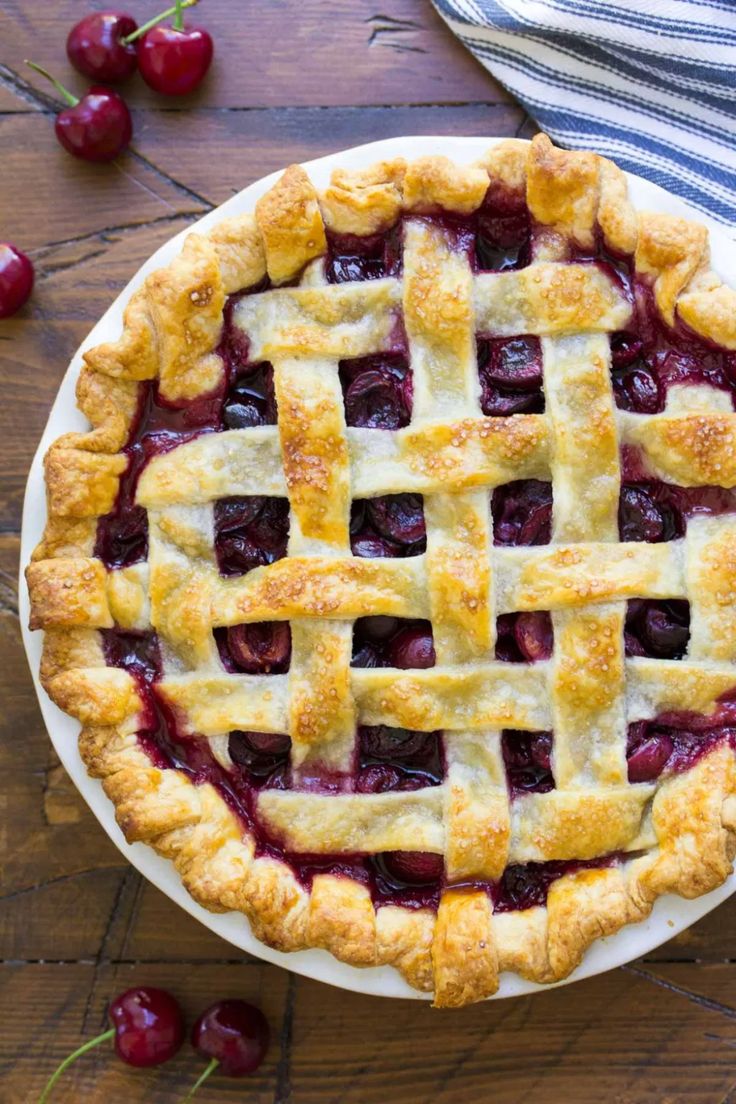 a cherry pie on a plate with cherries around it