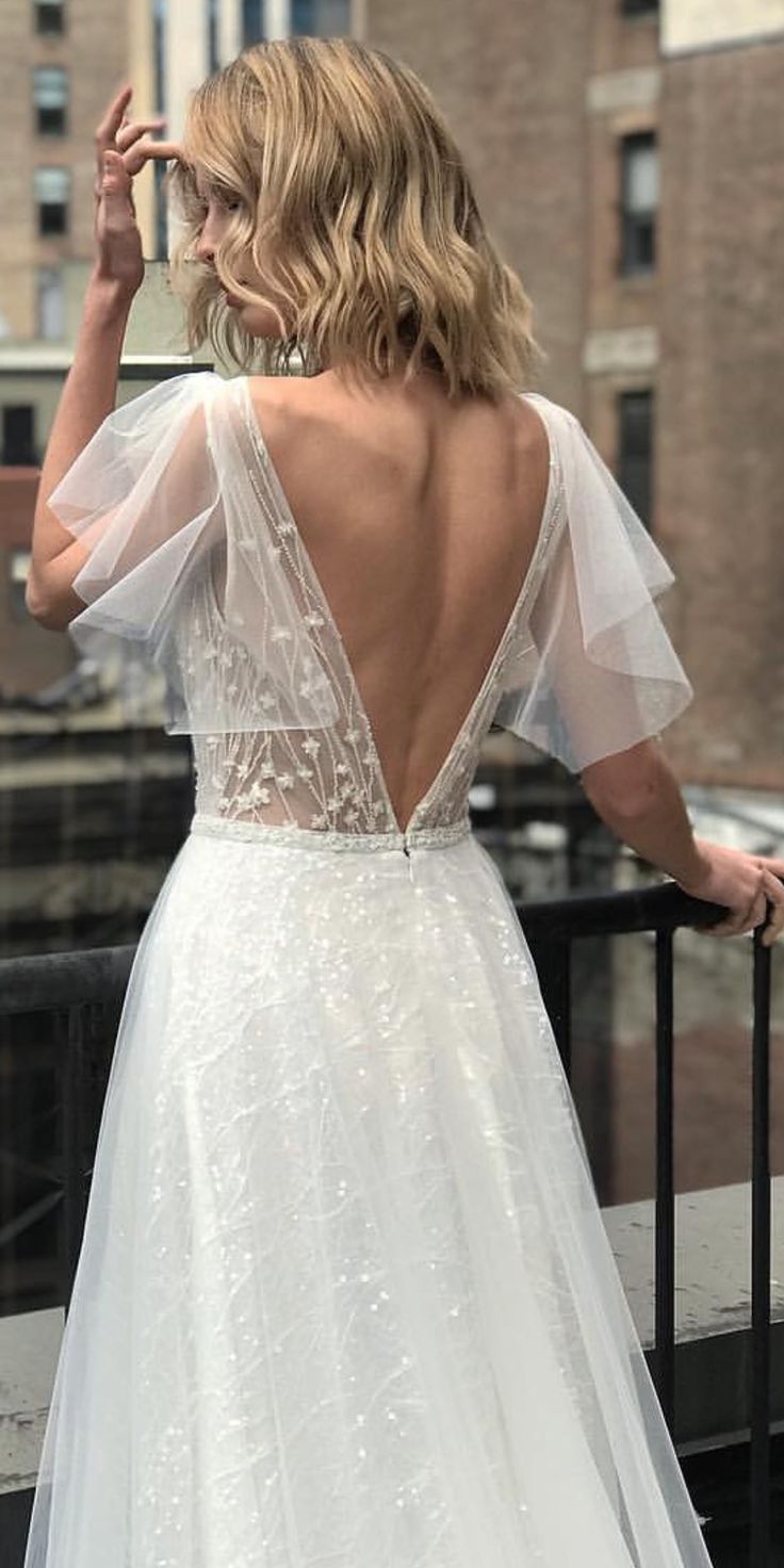 a woman in a white wedding dress standing on a balcony looking out at the city