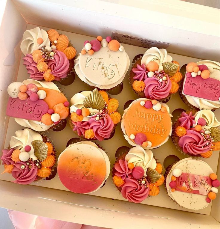 a box filled with lots of cupcakes covered in frosting and decorations on top of each other