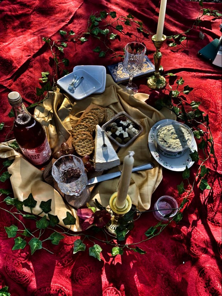 a table topped with plates and glasses filled with food on top of a red cloth