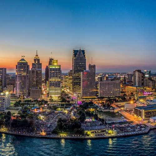 an aerial view of a city at night with the sun setting over the water and buildings in the foreground