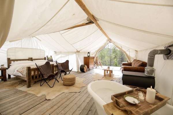 the interior of a large tent with wood floors and white walls, including a bathtub