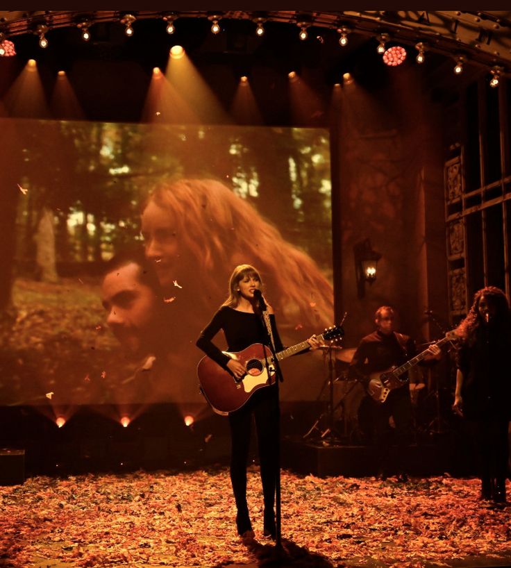 a woman standing on top of a stage holding a guitar