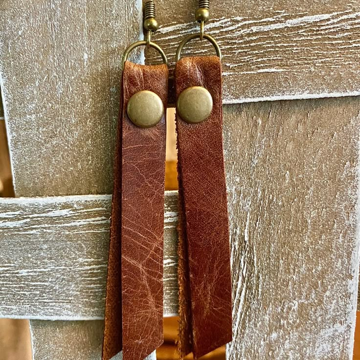 two brown leather earrings hanging from hooks