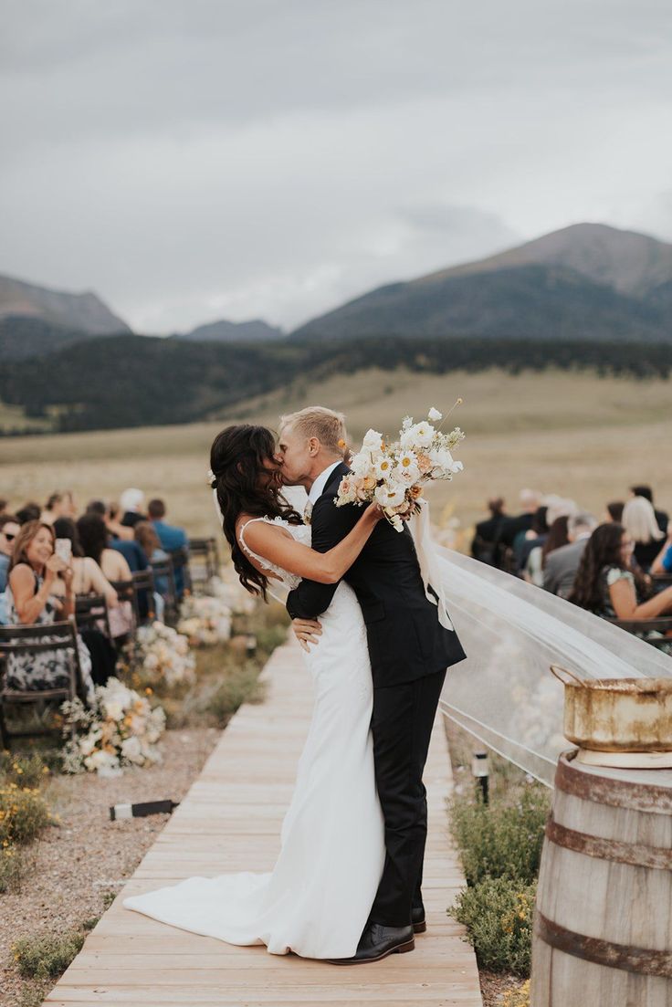 a bride and groom kissing in front of an outdoor ceremony