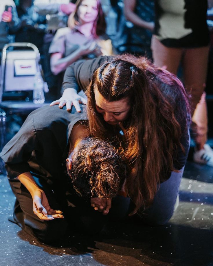 two people on the ground in front of a crowd with one person touching another's head