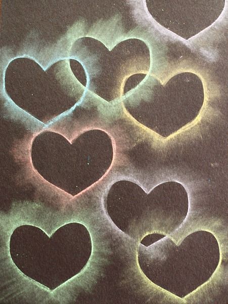 four hearts are drawn in the dark with colored chalks on paper and then light up