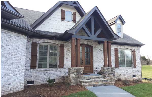 a brick house with brown shutters and stone steps