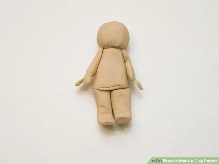 a clay doll laying on top of a white surface