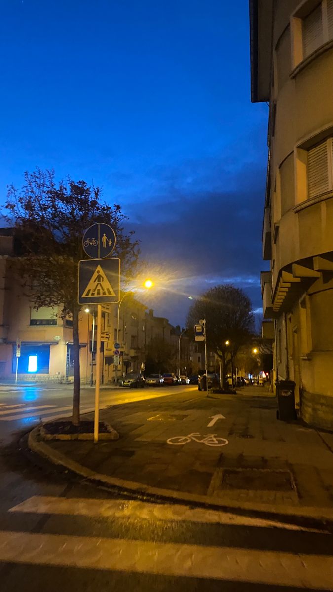 an empty street at night with no cars or people on the road and buildings in the background