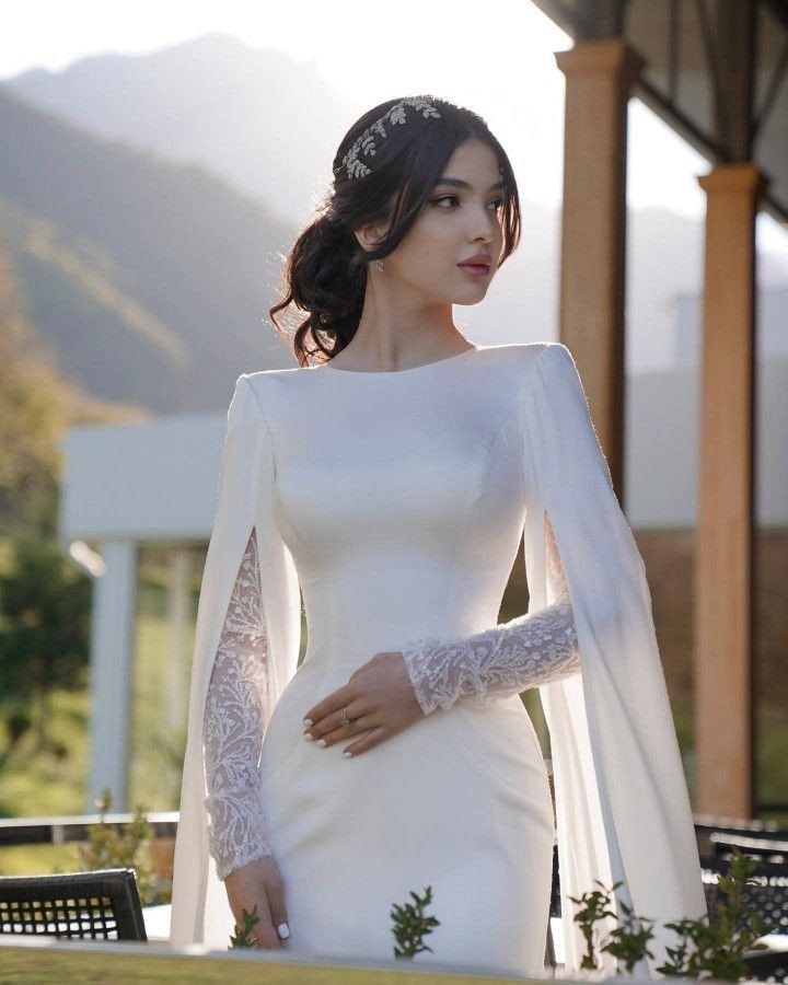 a woman in a white wedding dress with long sleeves and a veil on her head