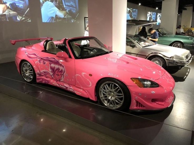 a pink sports car is on display in a showroom