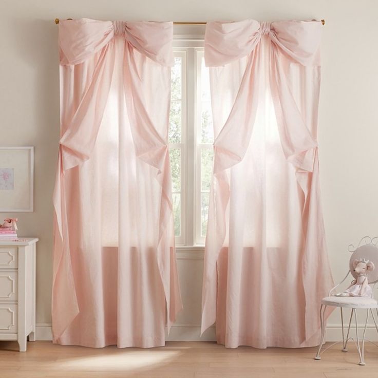 a pink curtain in a white room with a teddy bear sitting on a chair next to it