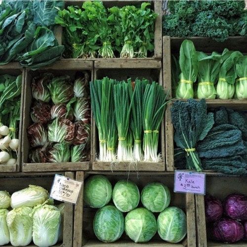 many different types of vegetables are displayed in wooden boxes with price tags on them for sale