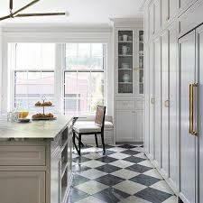 a kitchen with white cabinets and black and white checkerboard flooring on the walls