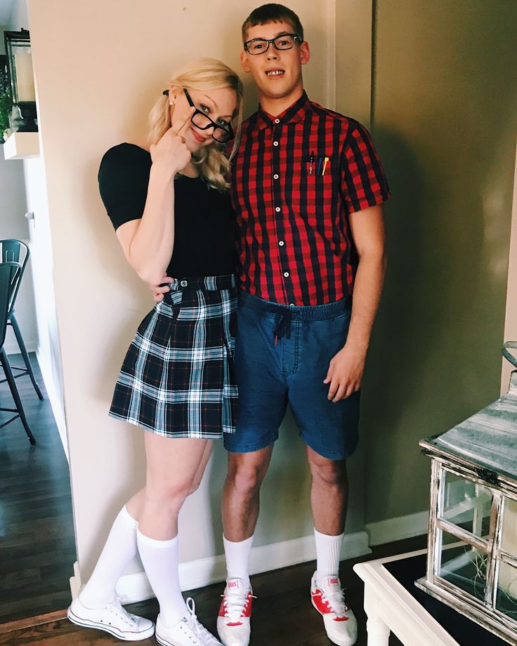 a man and woman standing next to each other in front of a wall wearing glasses