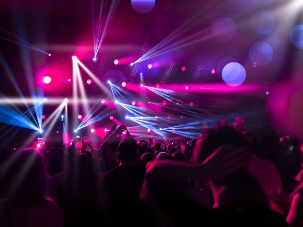 a crowd of people at a concert with their arms in the air and lights on