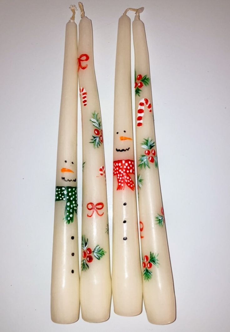 four white candles with christmas decorations on them