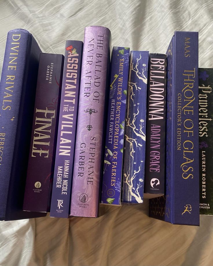 a row of purple books sitting on top of a bed next to an unmade sheet