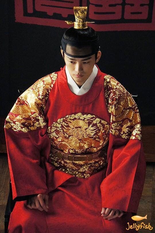 a man in a red and gold costume sitting down