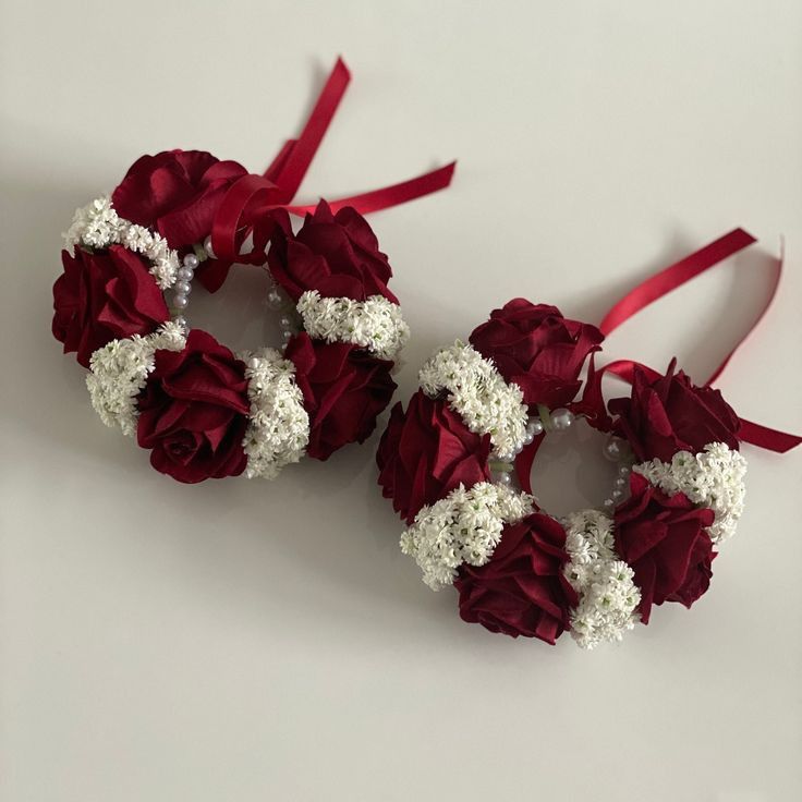 two red and white flowers are tied to each other with ribbons on the sides,