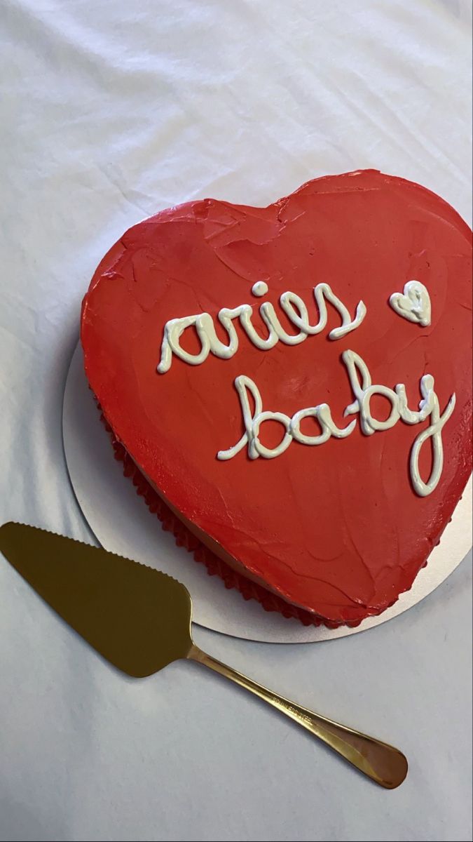 a heart shaped cake with the words hero baby written on it next to a spatula