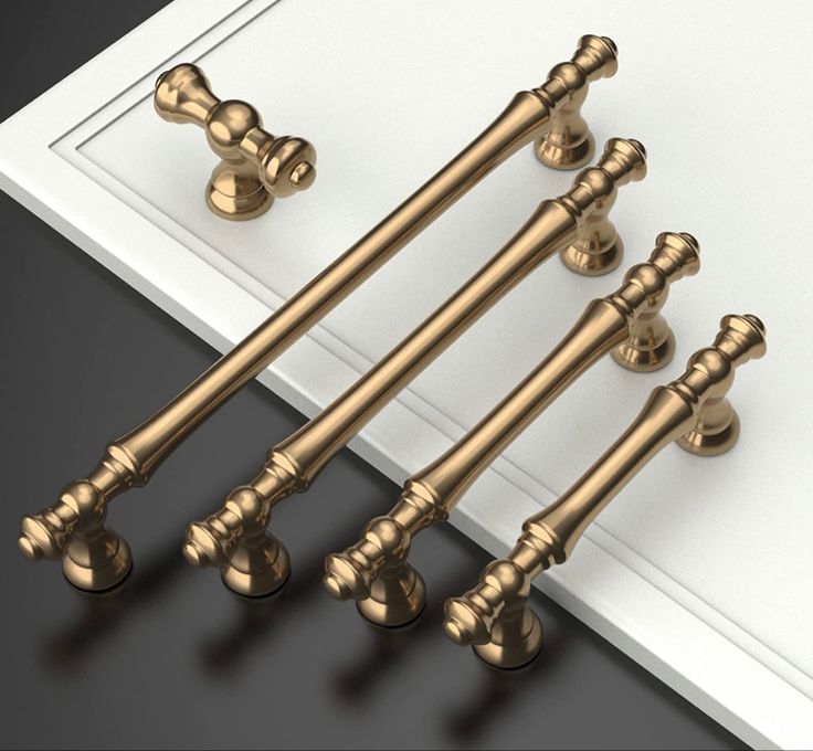 four golden handles and knobs on a white door