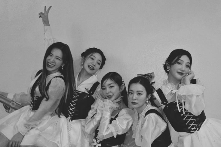 black and white photo of four women dressed in costume posing for the camera with their arms around each other