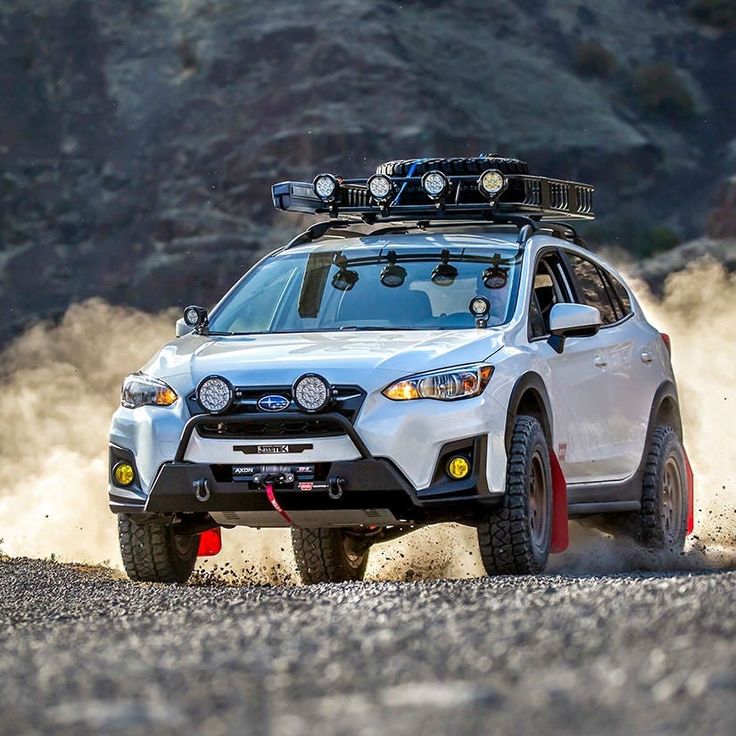 a white subarunt driving down a dirt road