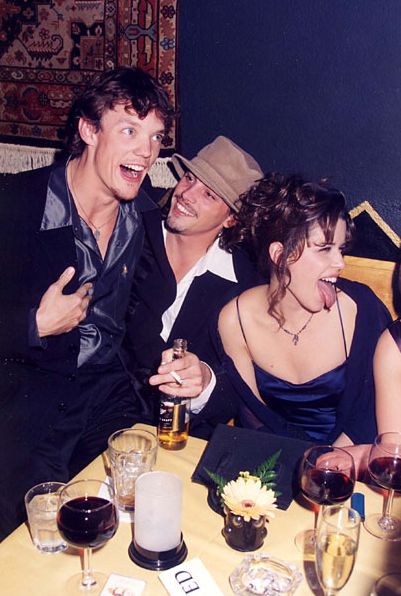 two men and a woman sitting at a table with wine glasses in front of them