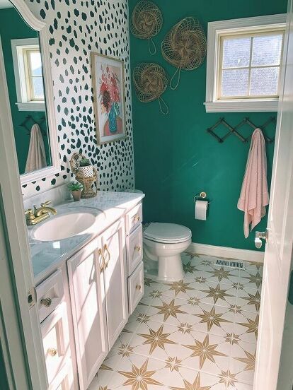 a bathroom with green walls, white and gold fixtures and patterned floor tiles on the wall