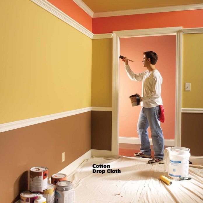 a woman is painting the walls in an empty room with yellow and red paint on it