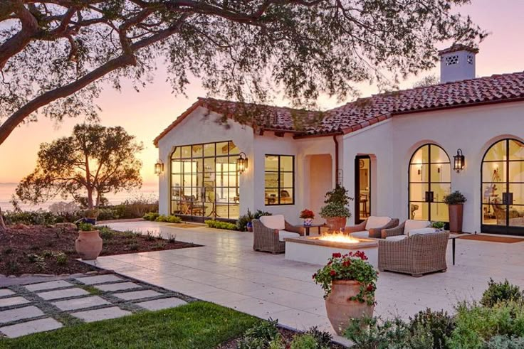 an exterior view of a house with large patio and seating area at sunset or dawn