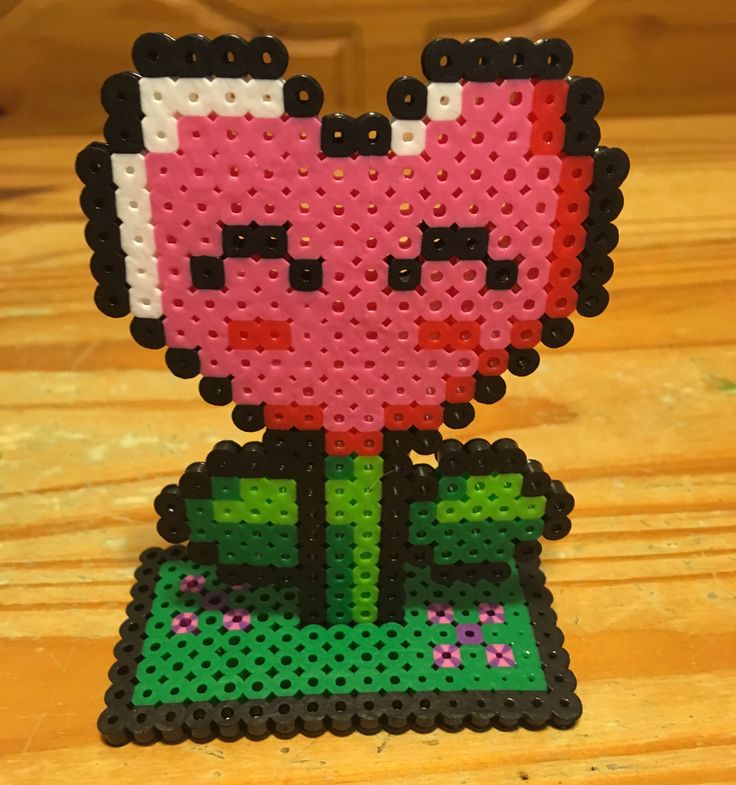 a pink flower made out of legos sitting on top of a wooden table