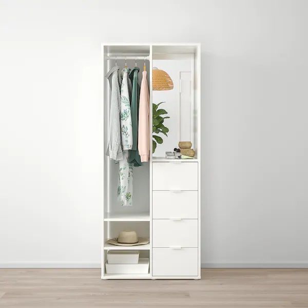 an open white closet with clothes hanging on the door and drawers in front of it