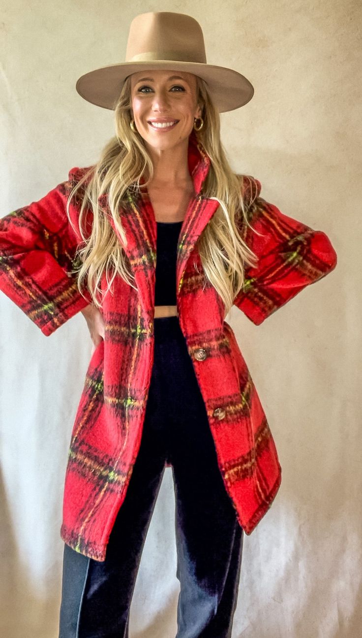 a woman wearing a red coat and hat posing for a photo with her hands on her hips