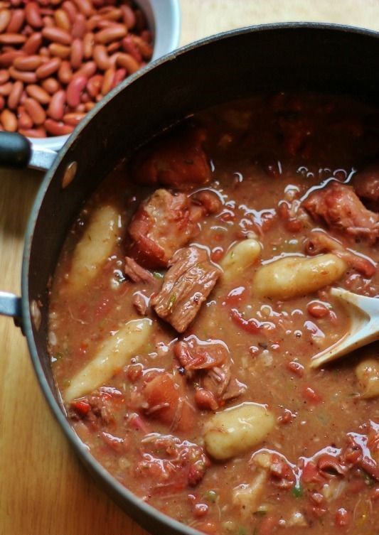 a pot filled with beans and meat on top of a wooden table