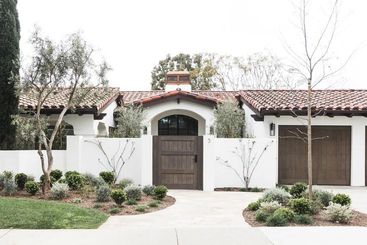 a white house with brown doors and trees