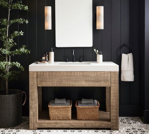 a white sink sitting under a mirror next to a wooden shelf with baskets on it