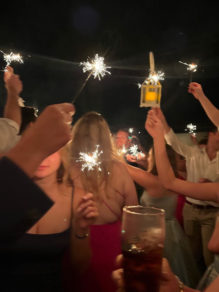 people holding sparklers in their hands at a party