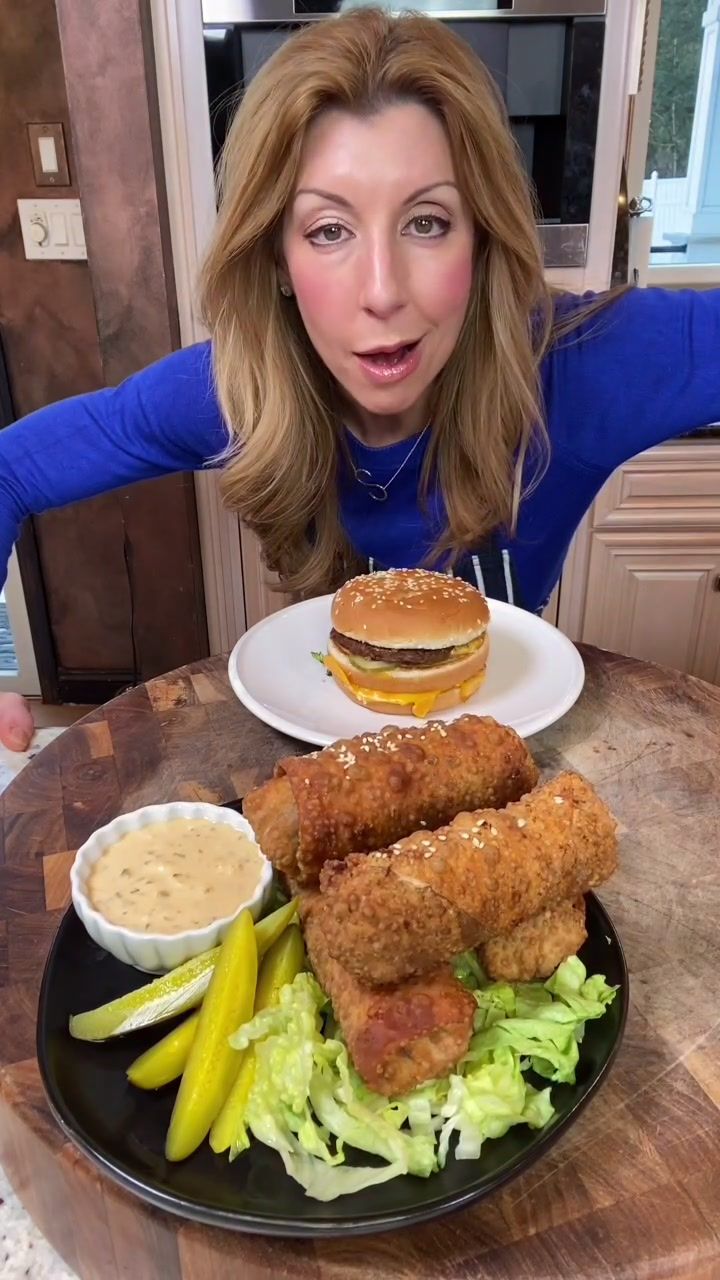 a woman sitting at a table with a plate of food in front of her,