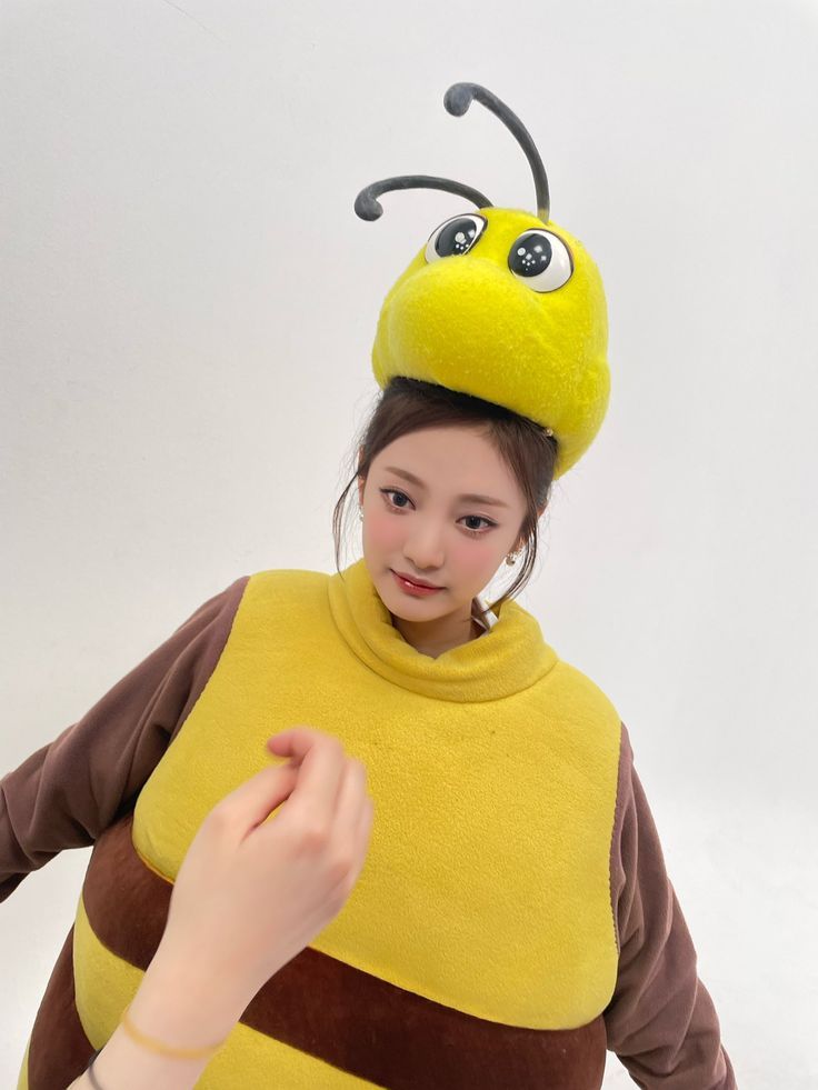 a girl in a bee costume pointing at the ladybug on her hat that she is wearing