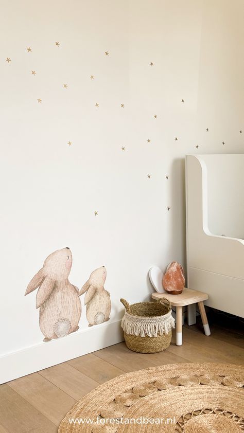 two white rabbits are sitting on the wall next to a small table and stools